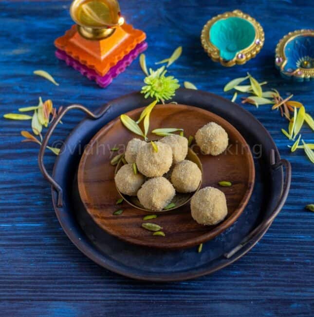square image of thinai laddu placed on a wooden plate with lamp lit on the side