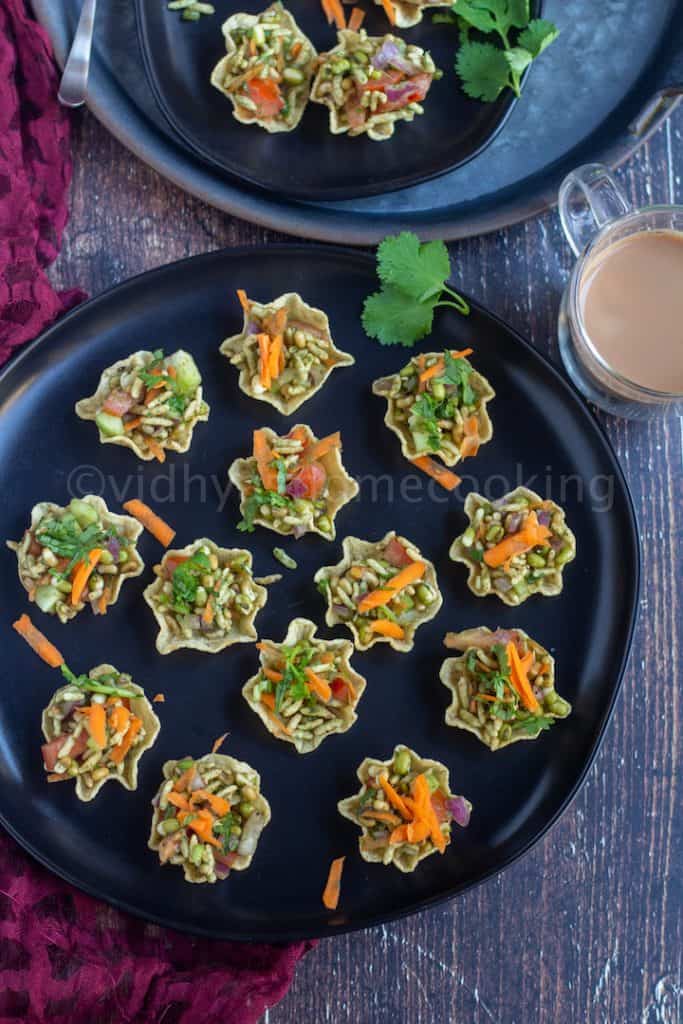 tortilla bhel cups placed on a black plate with tea on the side