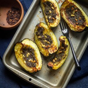 roasted acorn squash placed on a baking tray with chipotle chili flakes on the side