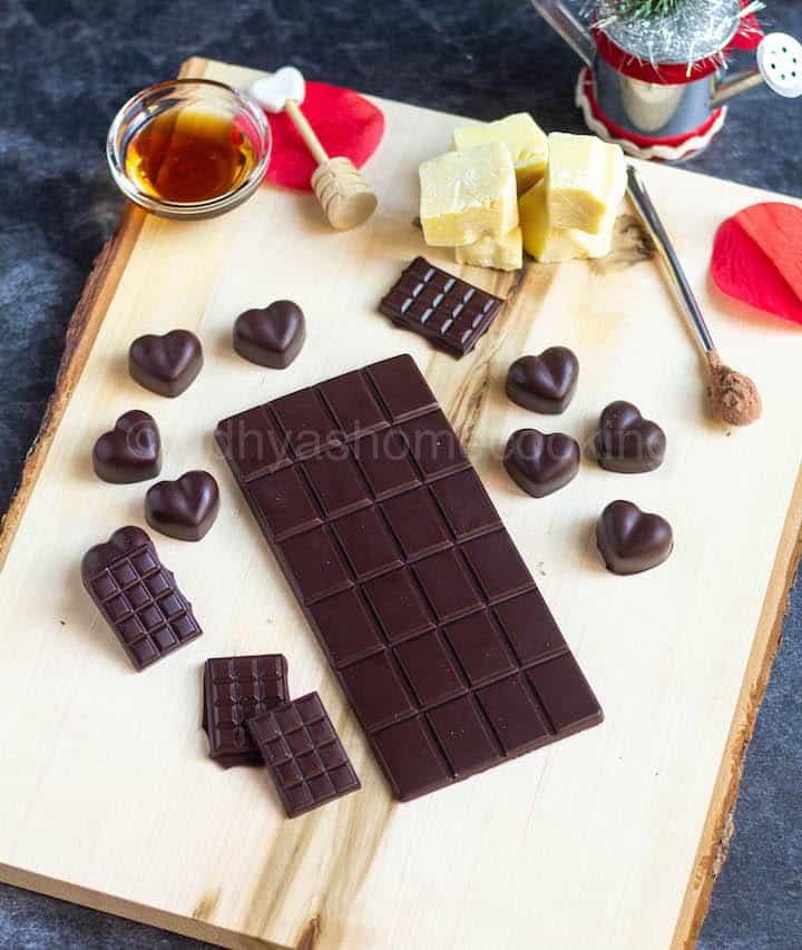 homemade dark chocolate bar and heart shaped ones placed on wooden board