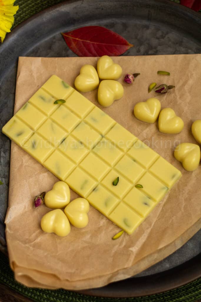 overhead shot of homemade white chocolate bar and heart shaped chocolates placed on a brown paper