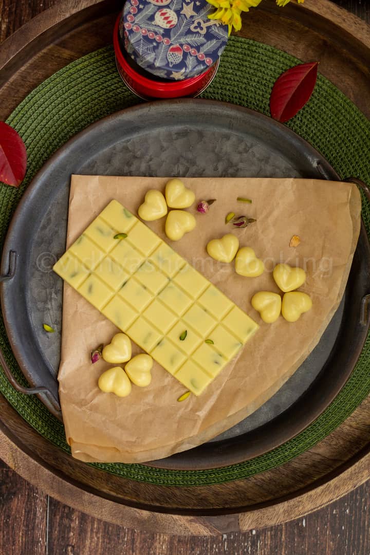 overhead shot of homemade white chocolate bar and heart shaped chocolates placed on a brown paper
