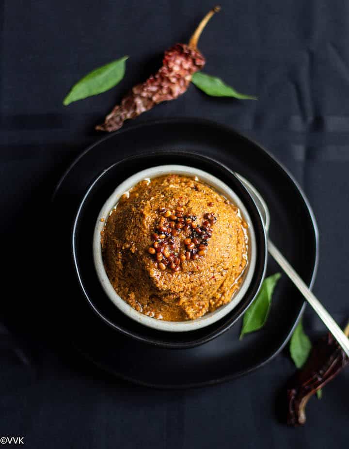 overhead shot of inji thogayal with some red chilies and curry leaves on the side