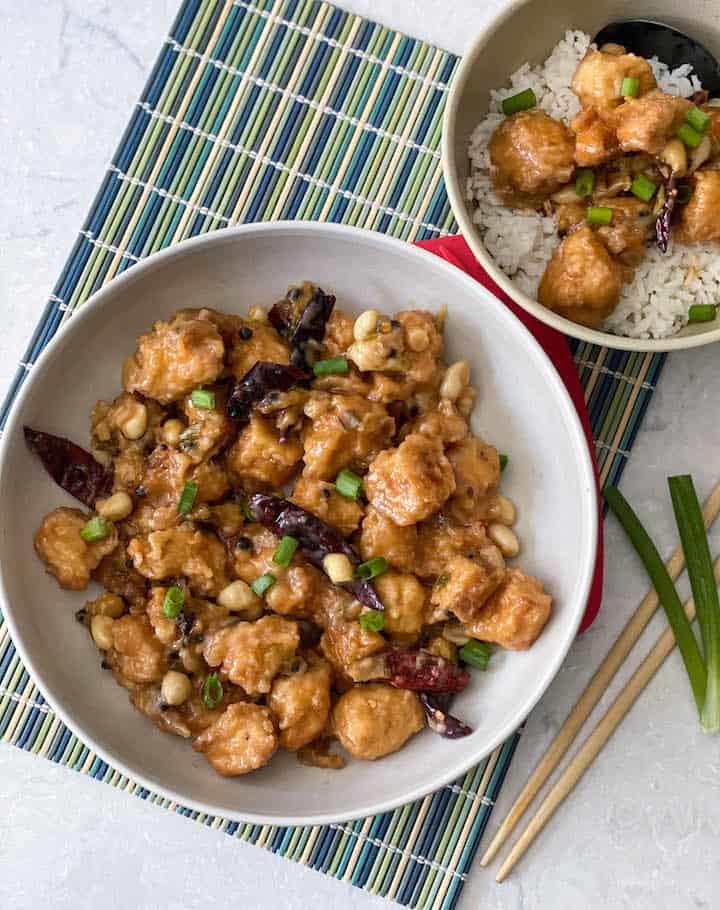 overhead shot of kung pao tofu placed on a white bowl with a side bowl filled with rice and tofu