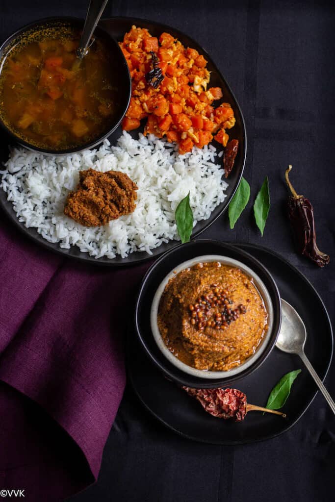 ginger chutney served in white bowl with a plate of rice, rasam and carrot stirfry