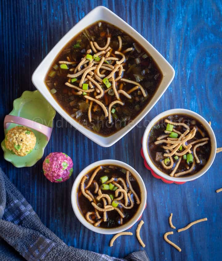 overhead shot of manchow soup served in two small bowls and one big bowl