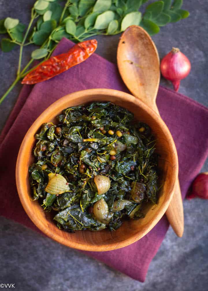 moringa leaves stirfry served in neem wood bowl placed on maroon towel