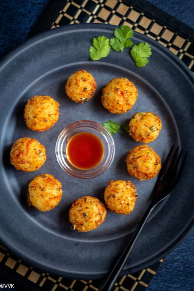 deep fried rice veggie and cheese balls served with tomato sauce in a plate with fork