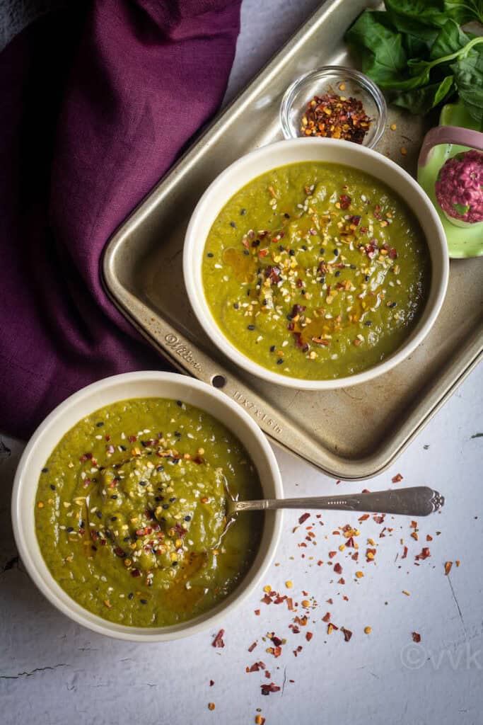 asparagus broccoli pea soup served in two bowls one placed on a baking tray