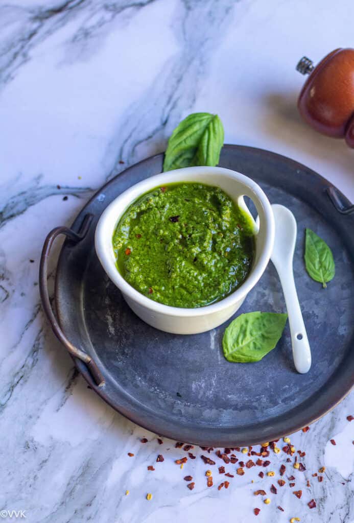 homemade pesto served in white bowl with a spoon on the side