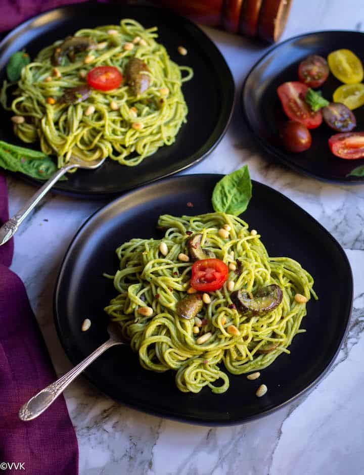 basil pesto pasta with mushrooms served in two black plates