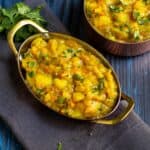 poori masala served in copper ware kadai with cilantro as a garnish