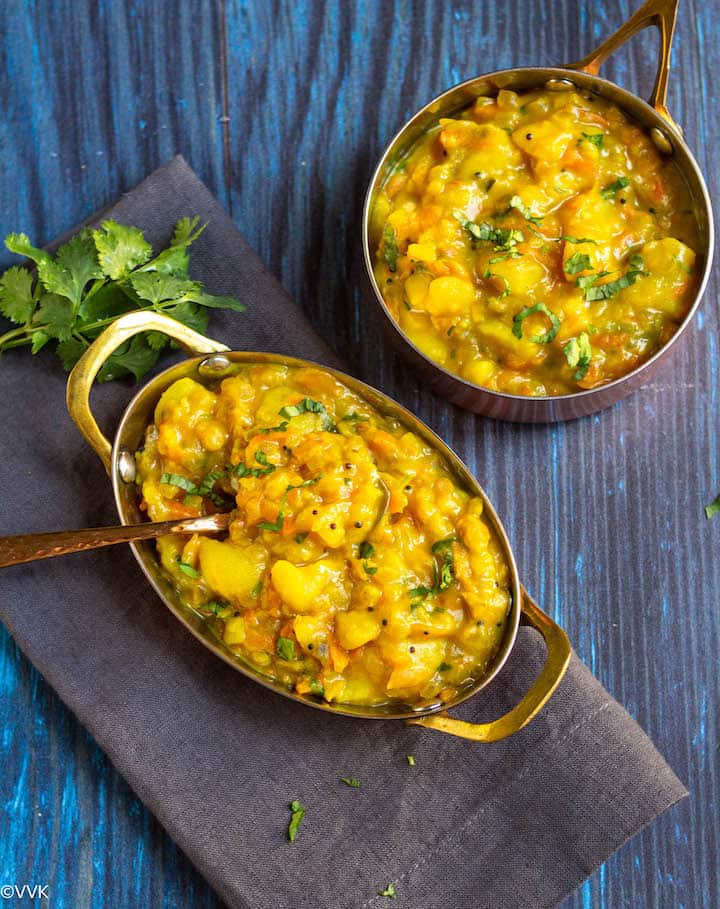 poori kizhangu masala served in copperware with a spoon inside placed on a gray towel