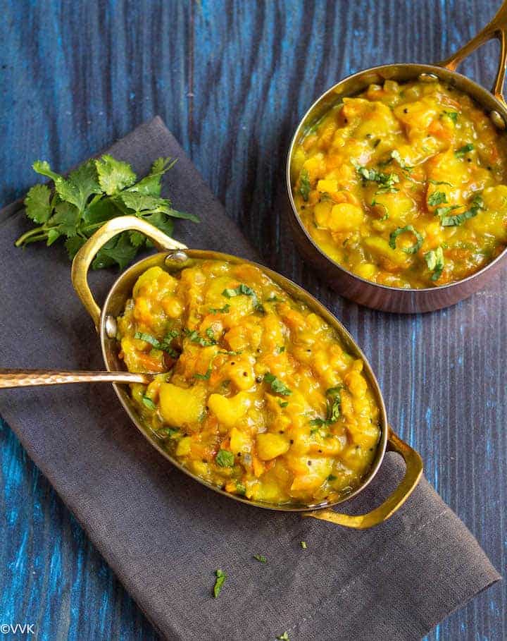 poori kizhangu masala served in copperware with a spoon inside placed on a gray towel