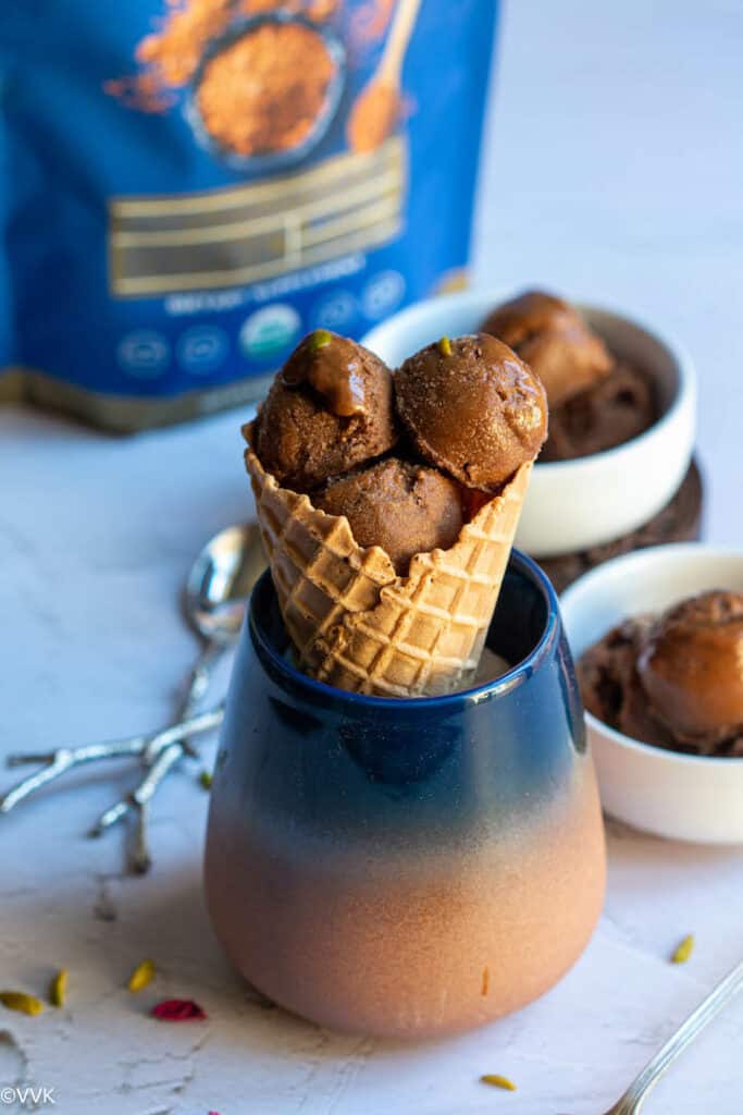 two ingredient chocolate banana ice cream served in waffle cone place in blue cup with some ice cream in white bowl
