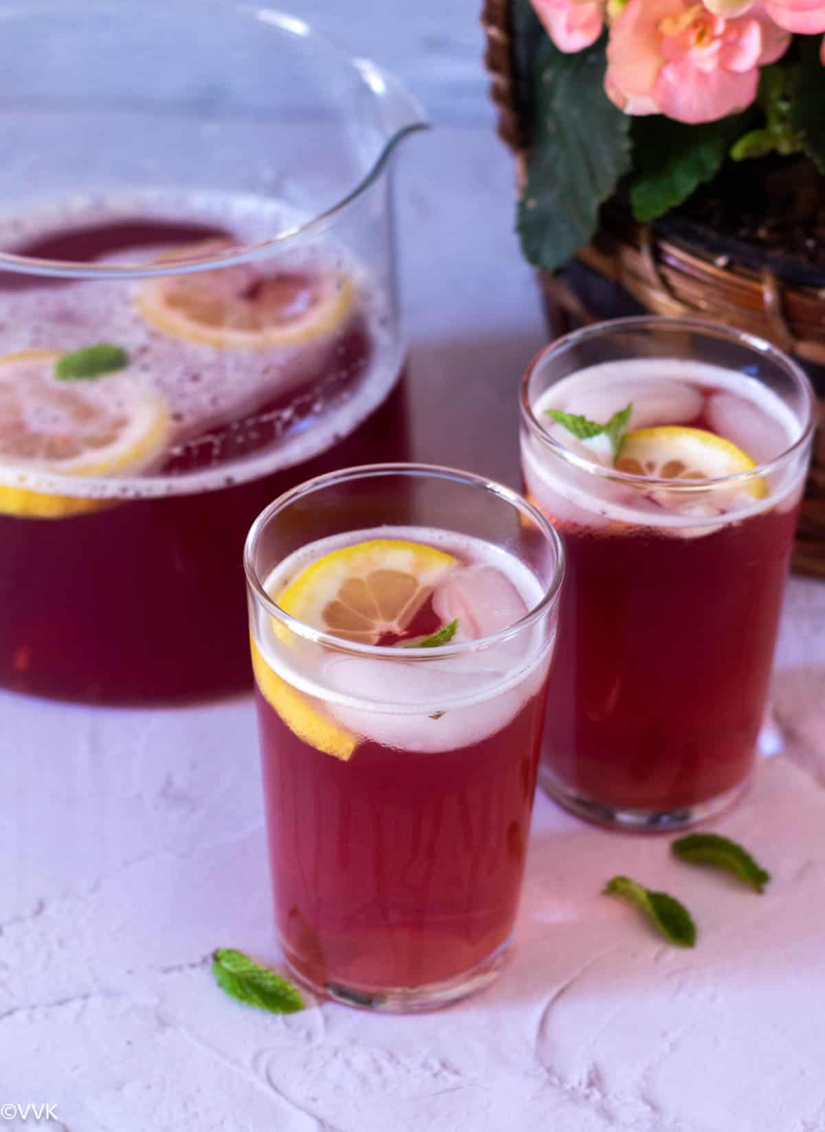 instant pot raspberry iced tea in two glasses with pitcher on the back