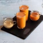 square image of thai tea served in glassed placed on a black slate board