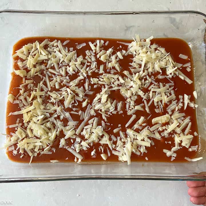 adding the bottom layer of cheese and sauce