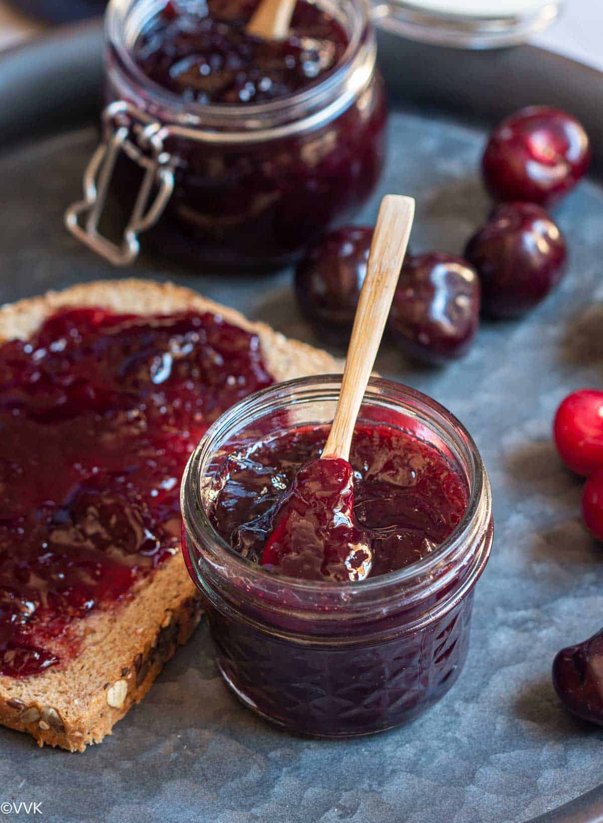 close up shot of instant pot cherry jam with bread smeared with the jam on the side