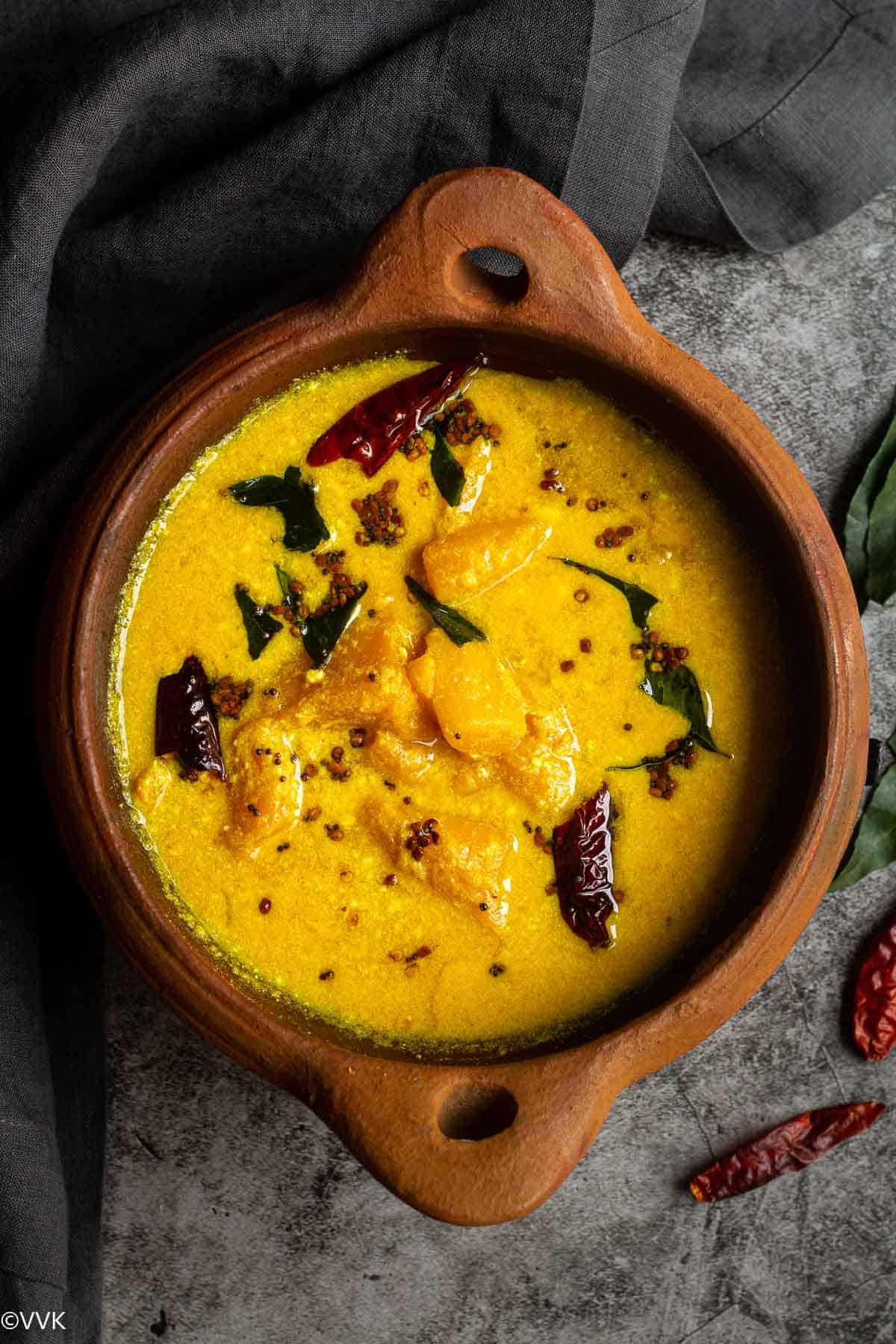 overhead shot of mango pulissery served in clay pot