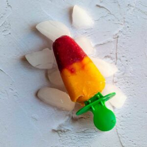 square image of mango raspberry popsicle placed on icebed