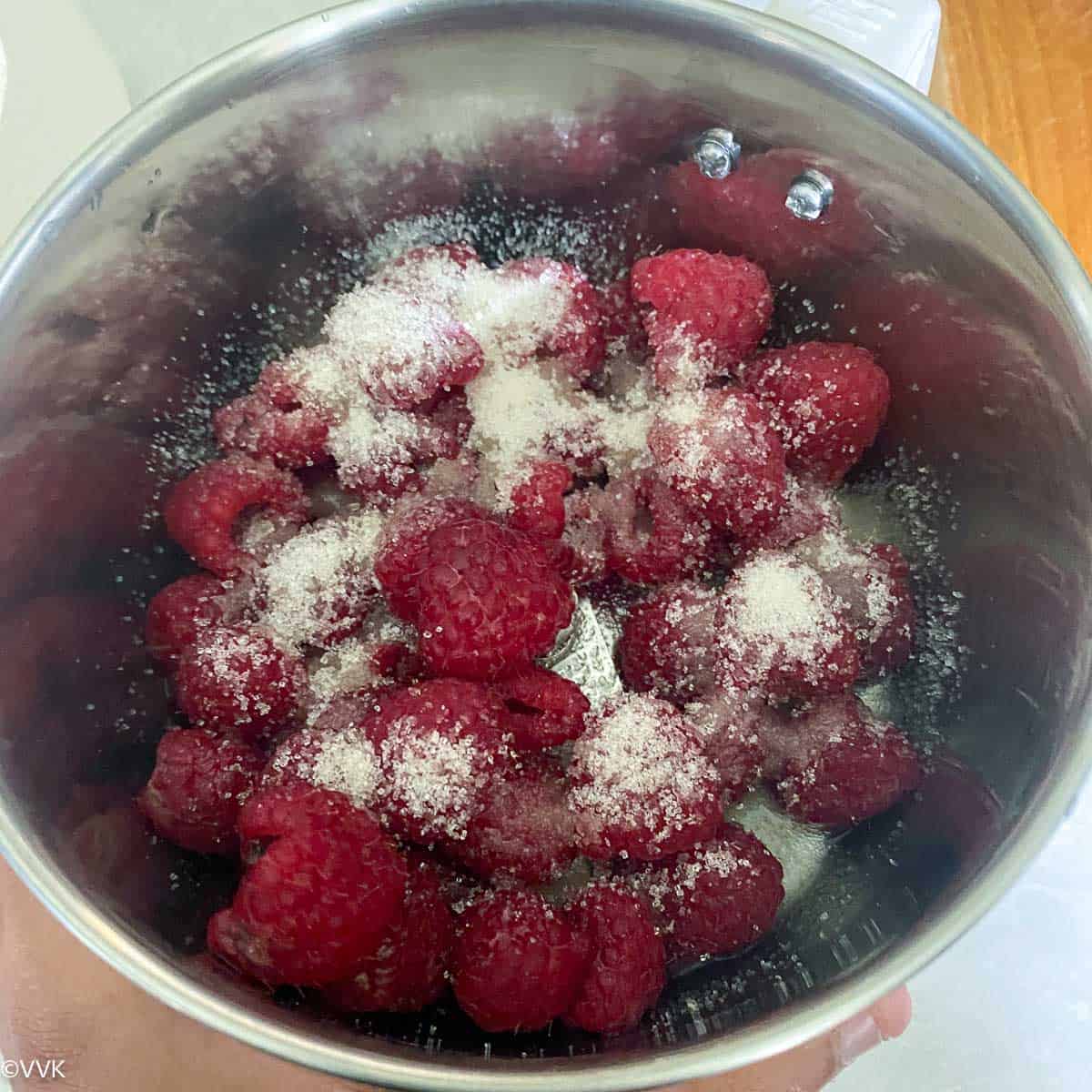 adding raspberries and sugar to mixer jar