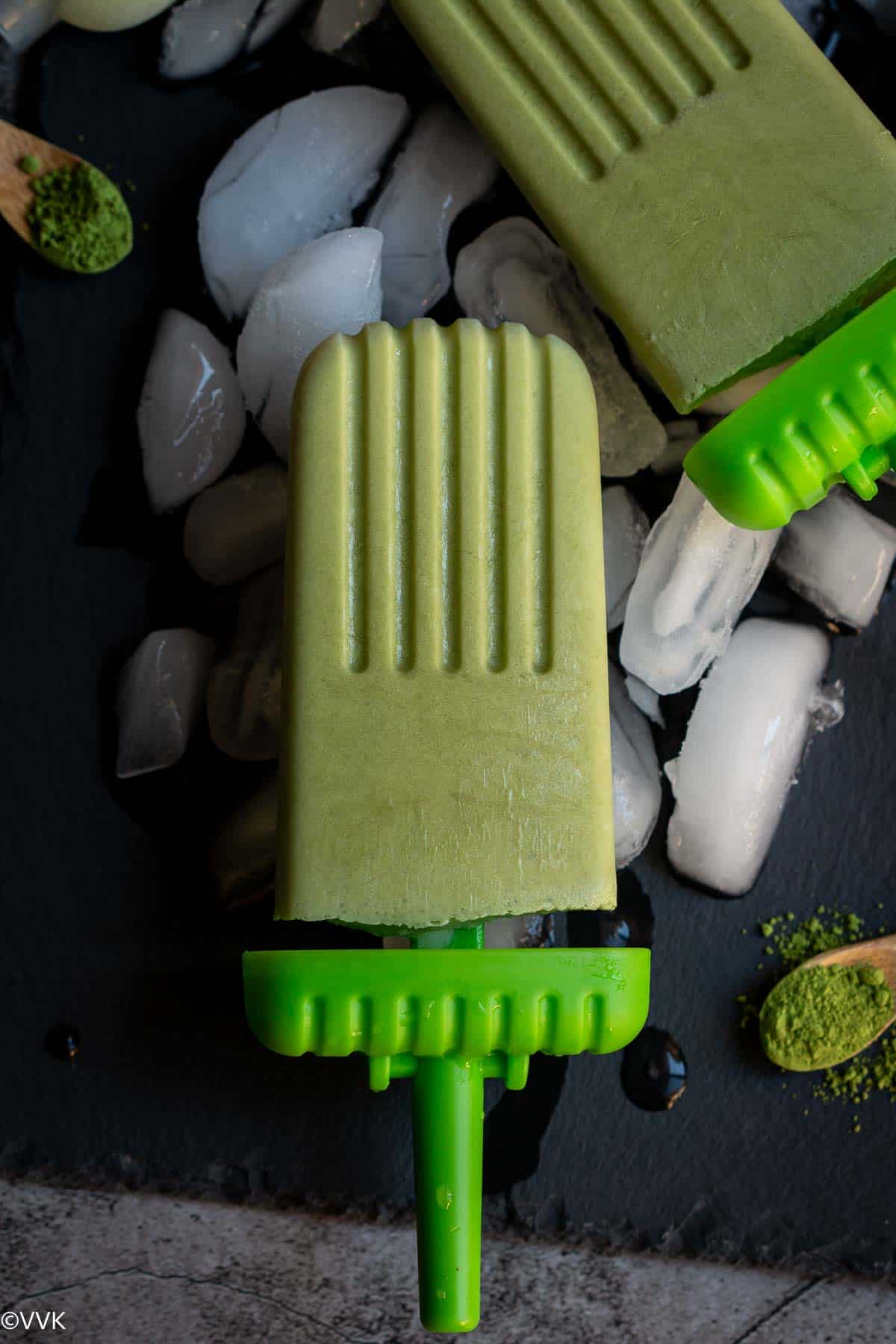 close up shot of matcha popsicle placed on ice cubes on a black slate board