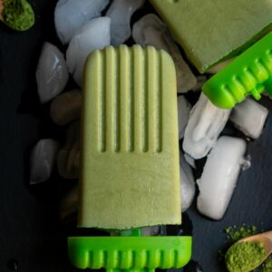 close up shot of matcha popsicle placed on ice cubes on a black slate board