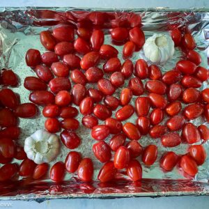 placing the tomatoes and garlic heads on baking tray