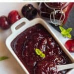 cherry chutney served in white bowl with a spoon inside with text overlay for pinterest