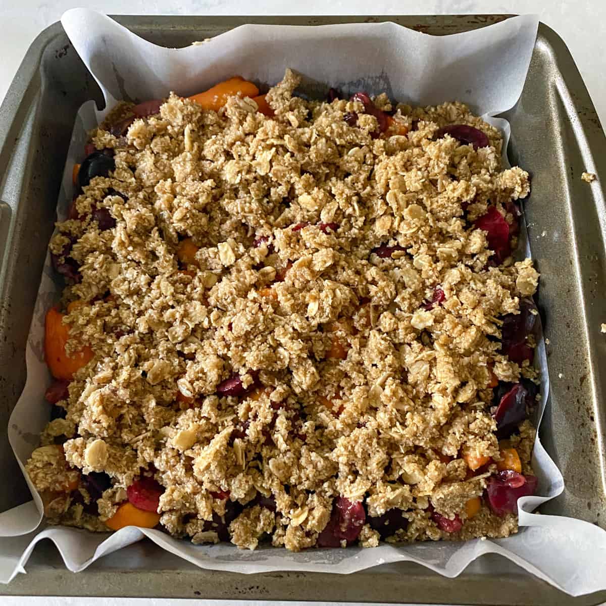 topping the fruit layer with oat flour crumb