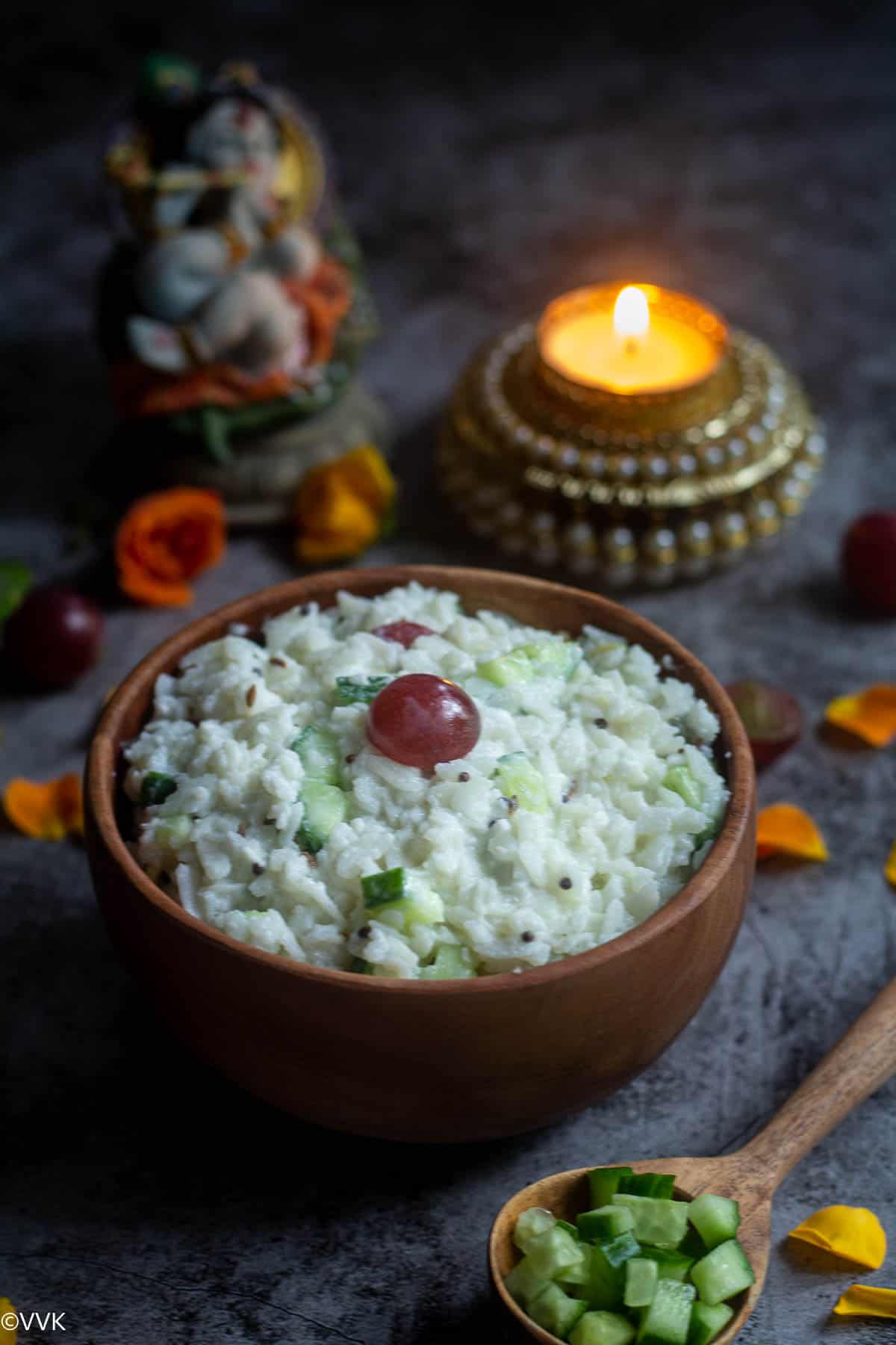 dahi poha served in wooden bowl with flower petals on the side and idol Krishna and candle on the top