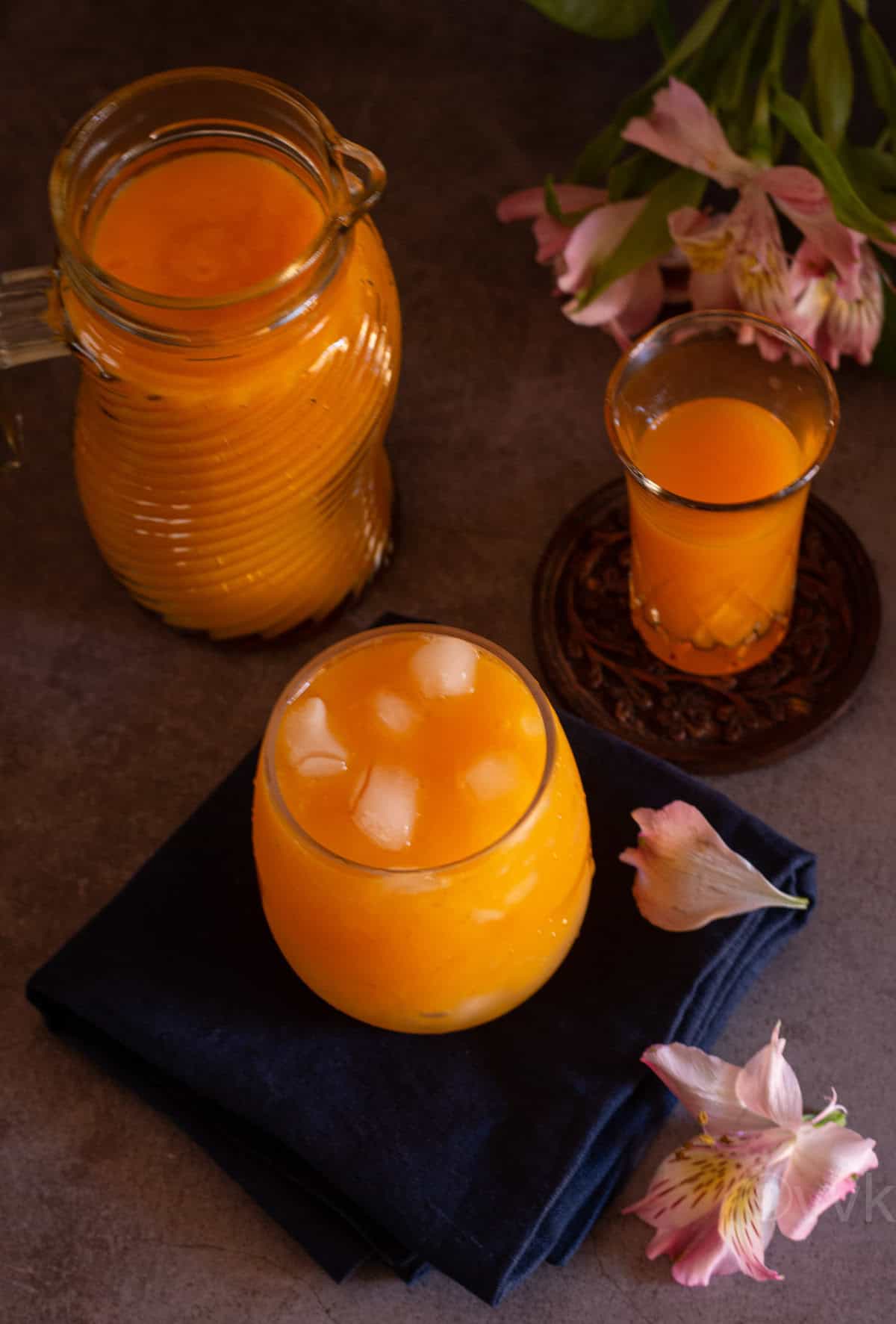 overhead angled shot of mango nectar with ice in a tall glass placed on blue napkin