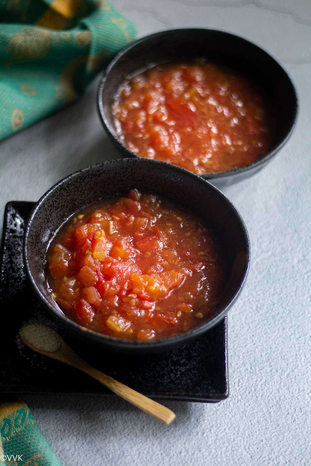 thakkali sweet pachadi made in microwave served in two black bowls with a fabric on the side