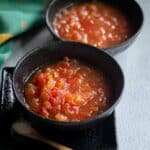 sweet tomato relish served in black bowl with text overlay for pinterest