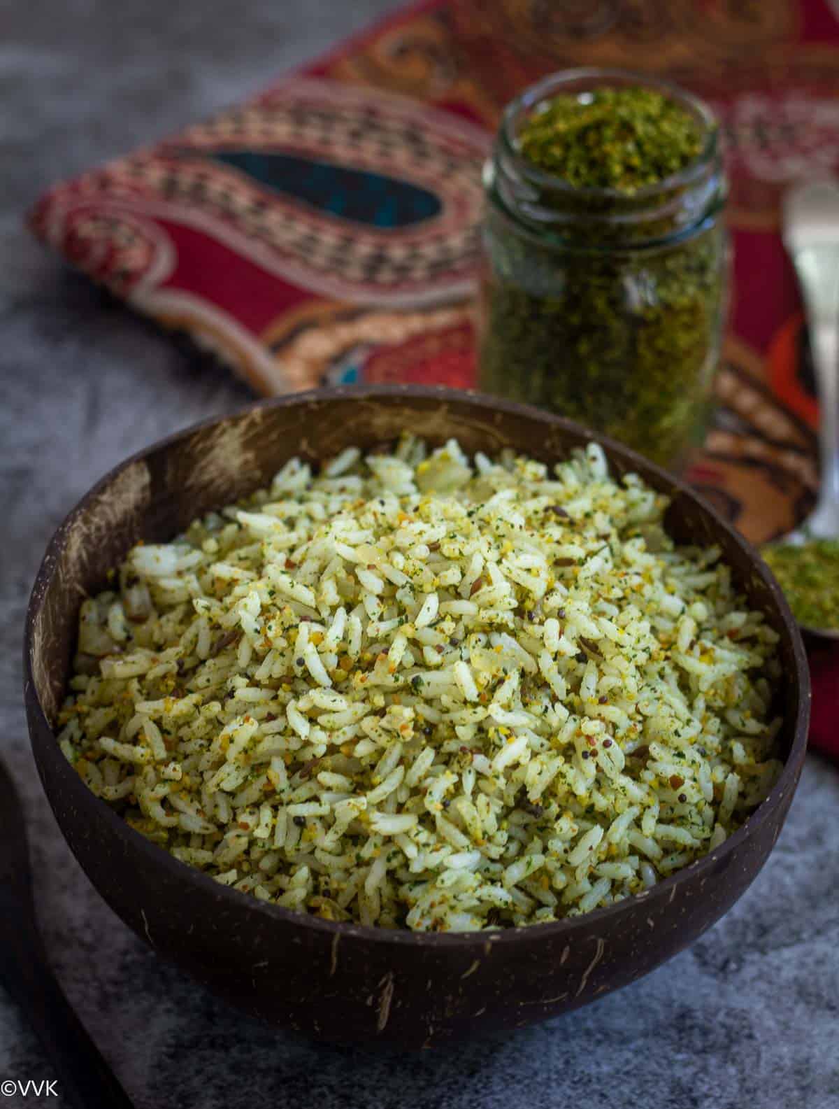 close up shot of cilantro rice served in coconut bowl with podi on the side