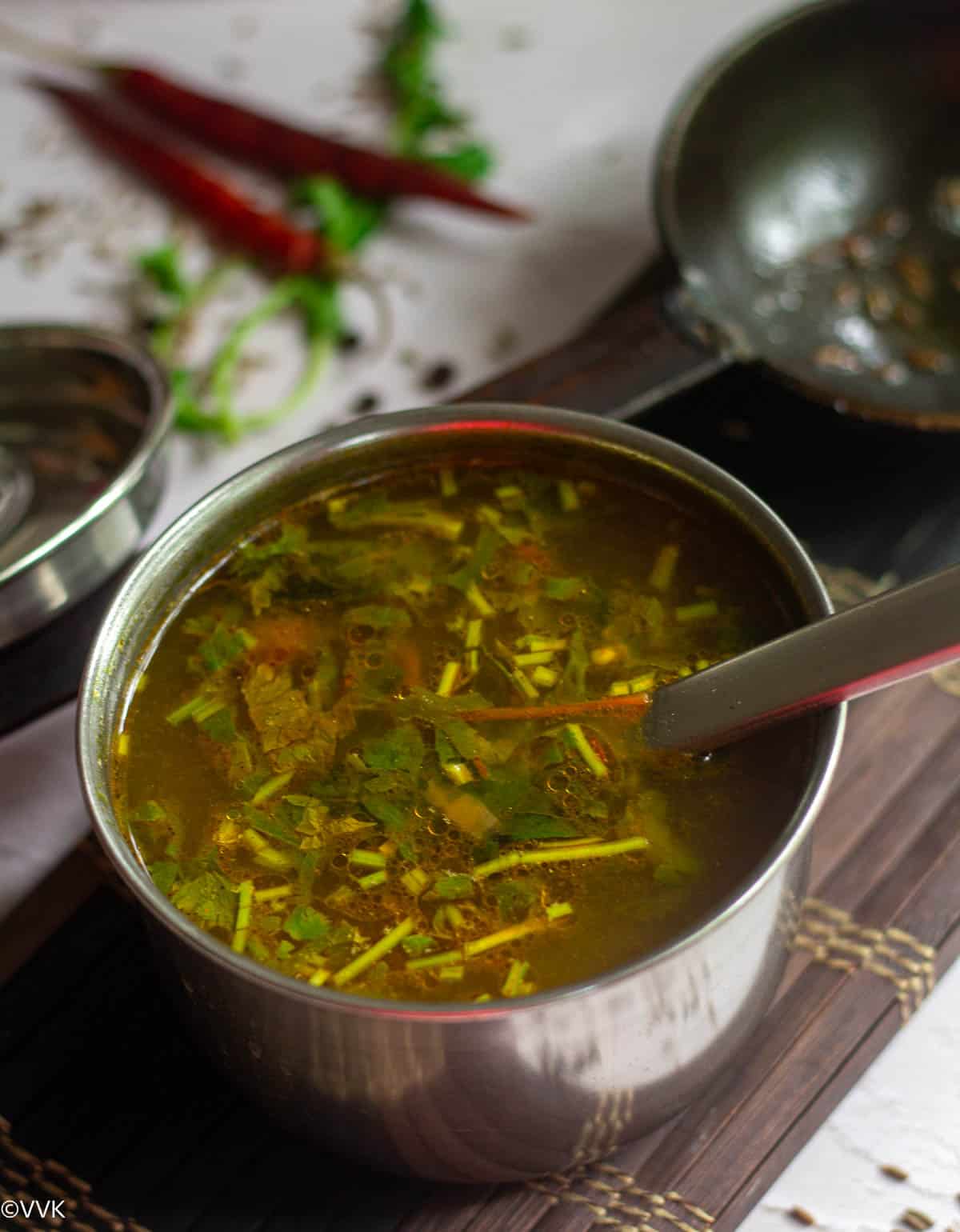 goddu saaru served in stainless steel bowl with spoon inside placed on mat