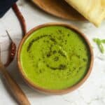 square image of coriander coconut chutney served with dosa in a wooden bowl and plate