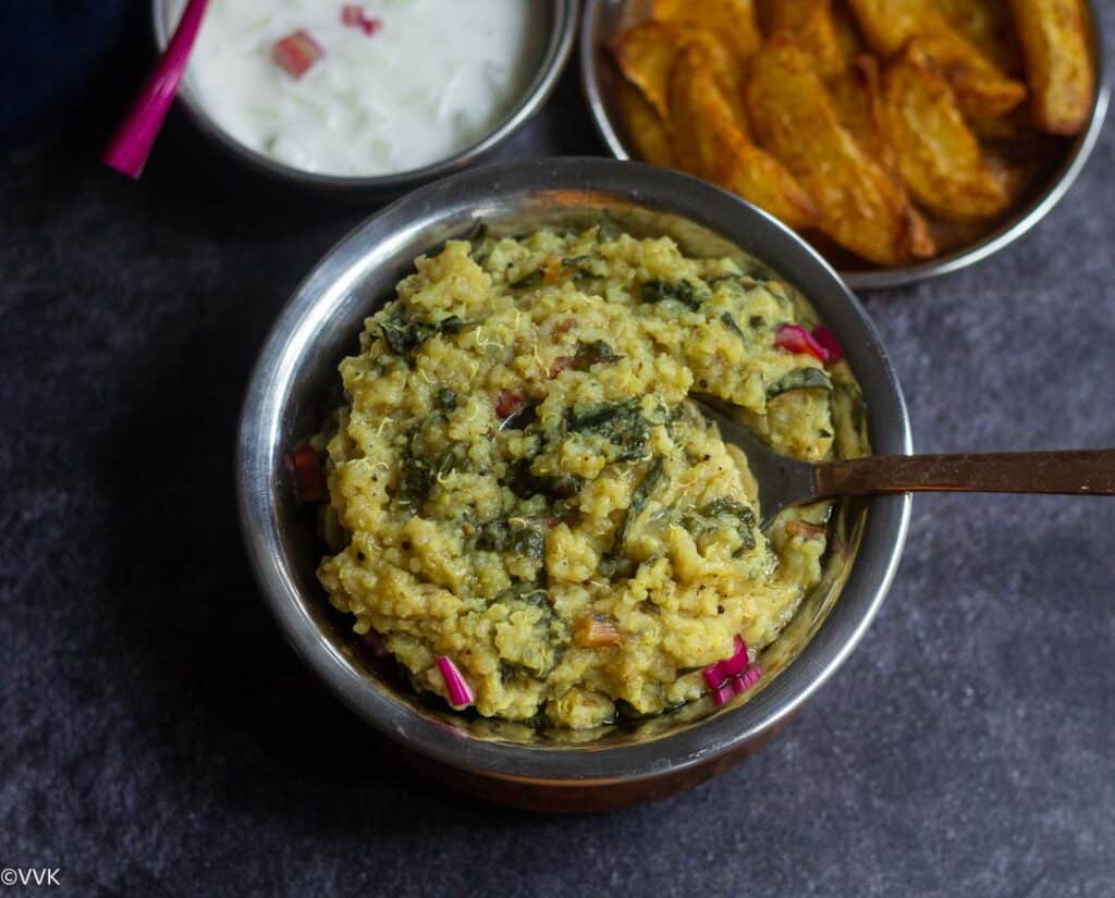 instant pot spinach rice served in brass bowl with spoon inside with a side of potato and raita