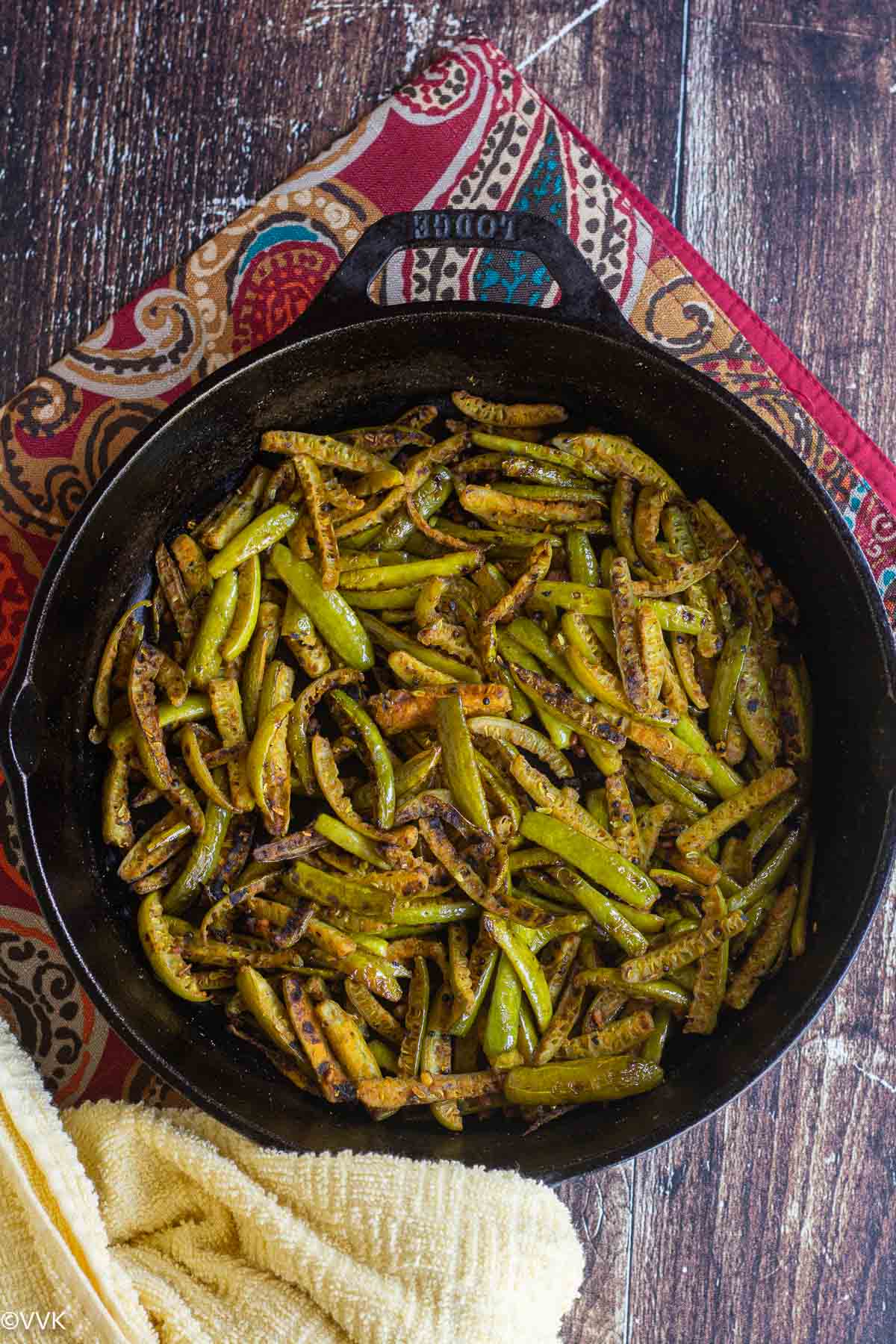 ivy gourd curry served in the cast iron pan placed on red mat