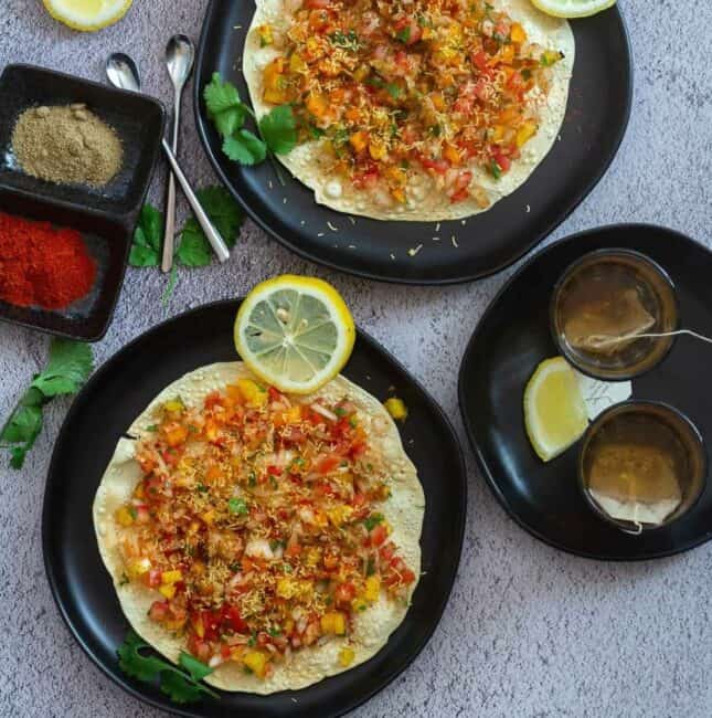 masala papad served in two plates with a side of tea and spices