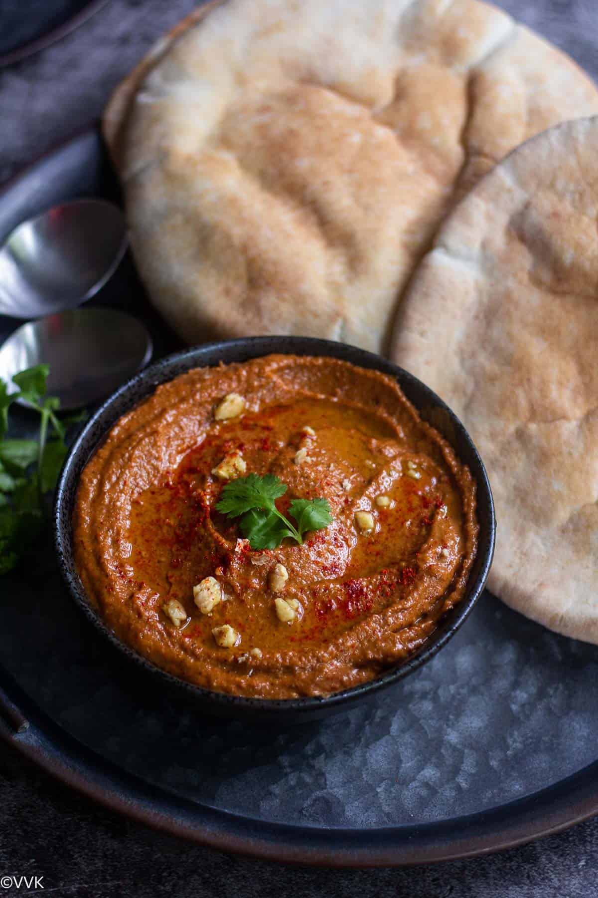 angled shot of roasted bell pepper dip served with pita bread