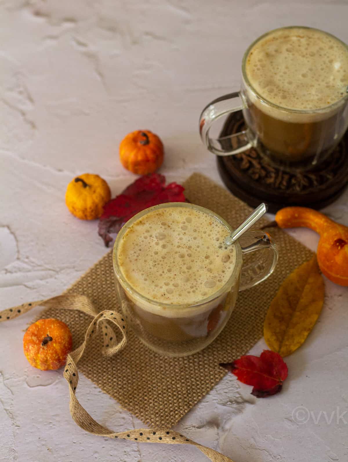 vegan pumpkin spice latter in two glasses with inside placed on a burlap cloth