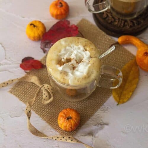 square image of pumpkin spice latte served in a glass placed on a burlap cloth