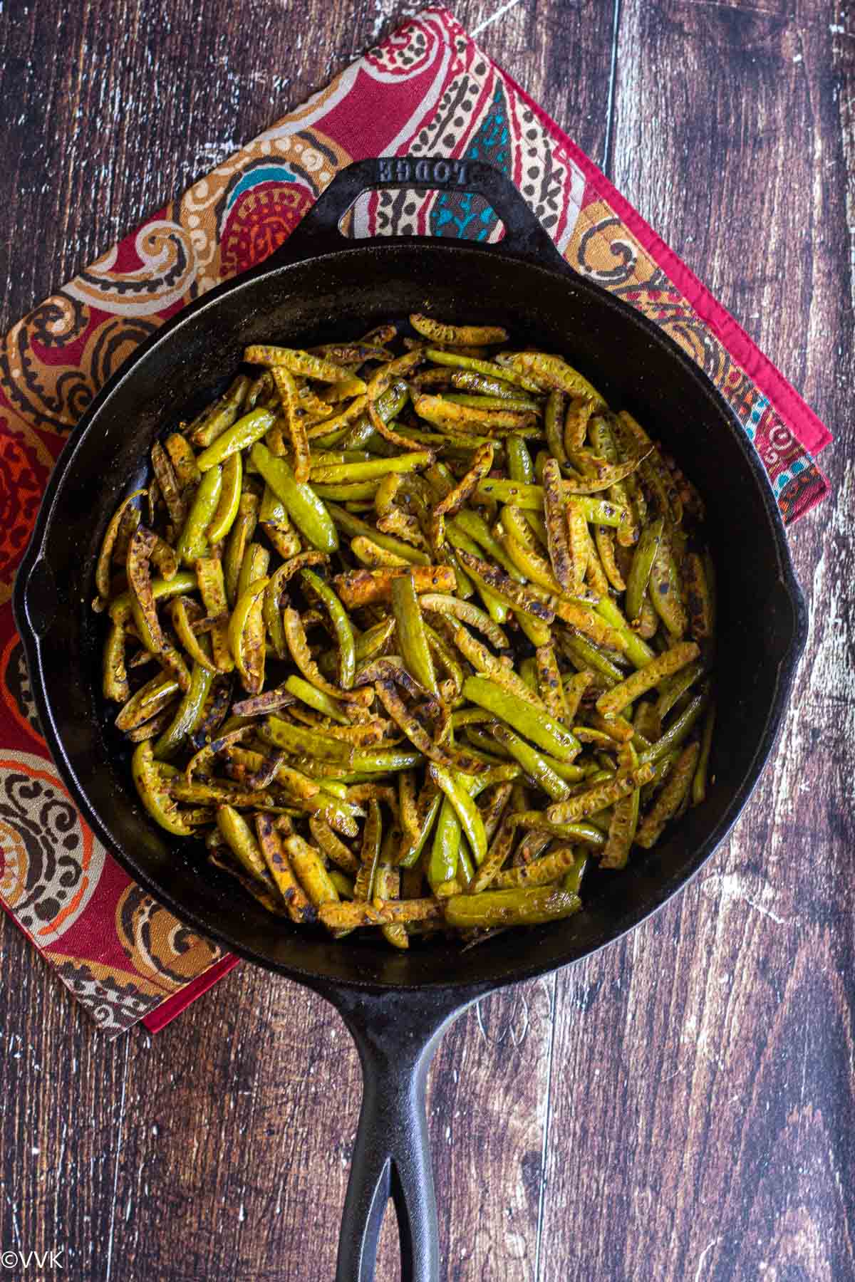 easy kovakkai poriyal cooked and served in cast iron pan placed on red mat