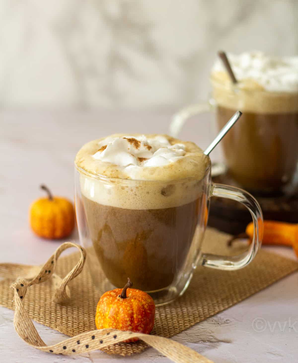 straight angle shot of pumpkin spice latte topped with coconut whipping cream