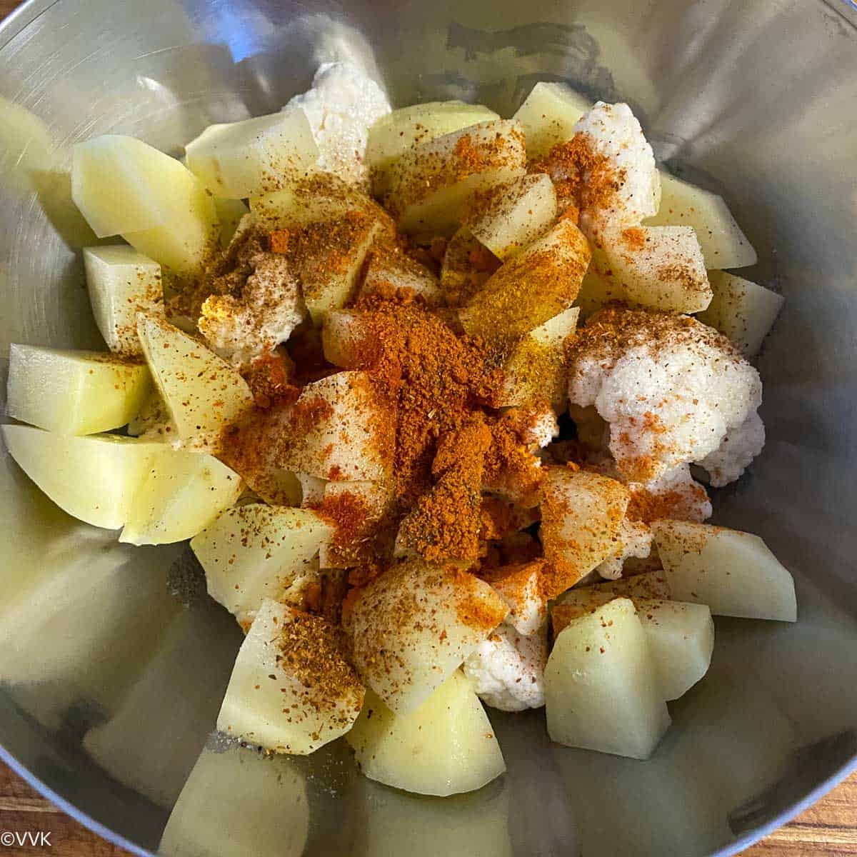 adding spices to the cauliflower and potatoes