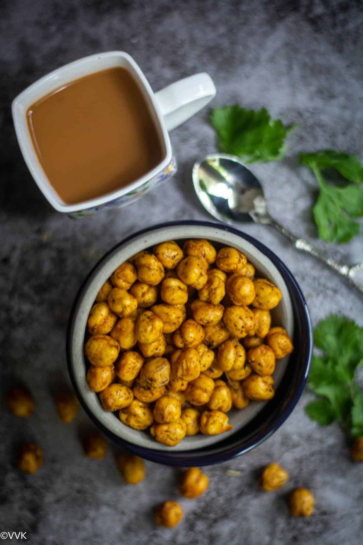 flowing shot of roasted chickpeas and few scattered below served with tea