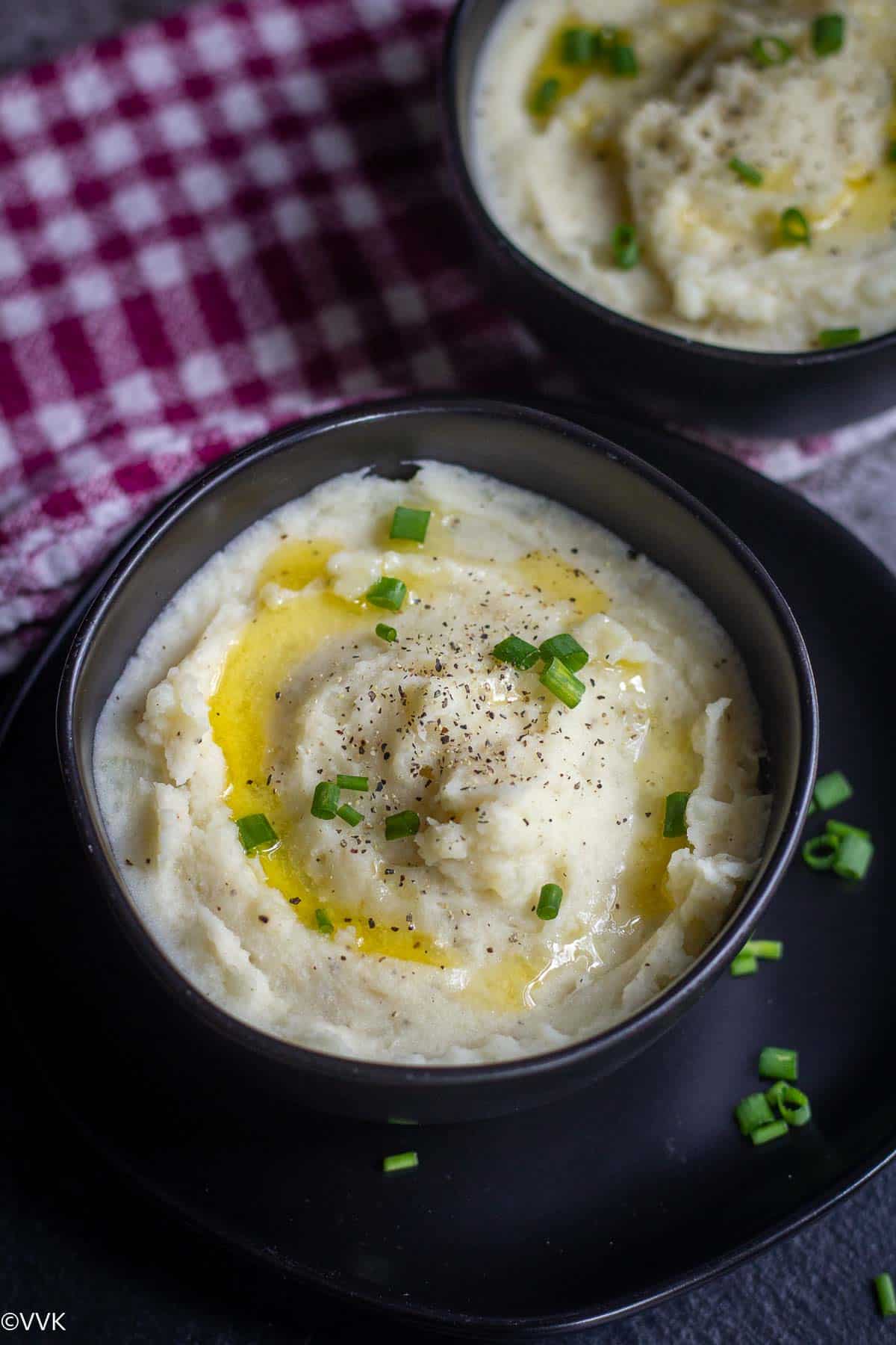 instant pot mashed potato topped with butter and chives served in black bowl