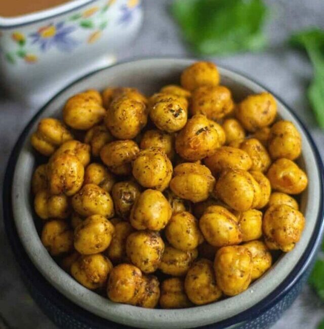 crunchy air fryer chickpeas served in bowl with tea on the side and cilantro as a garnish